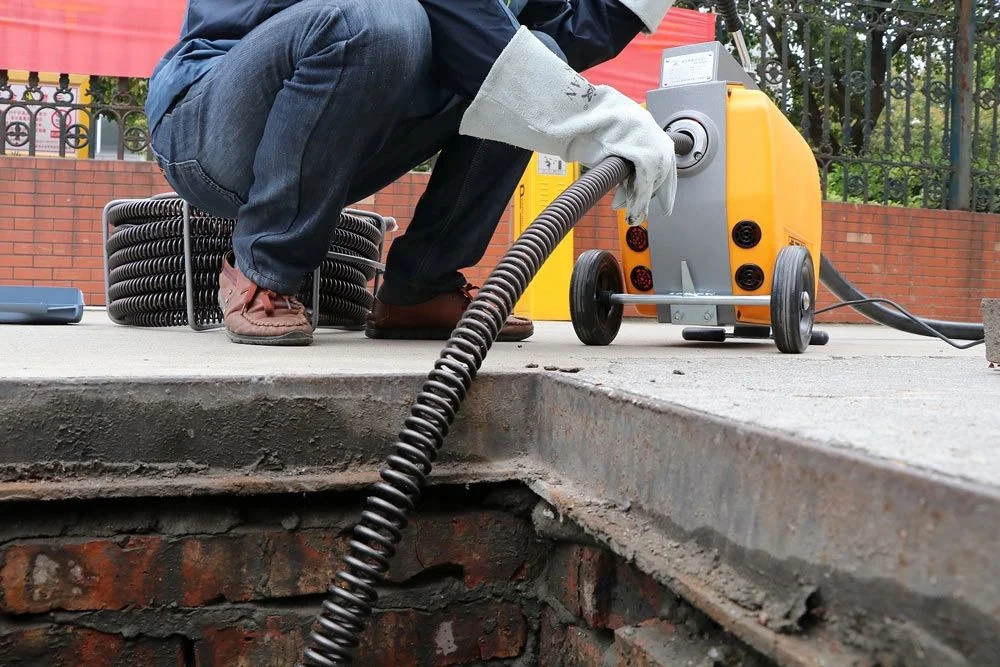 Plomero profesional destapando cañería con sonda eléctrica en Bogotá
